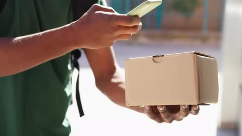 African American Man Using Smartphone in a Box Before to Deliver It
