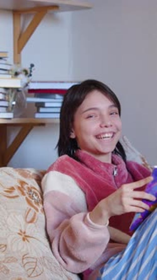 Teenager Girl Reading Book While Sitting at Home on Sofa
