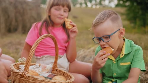 Siblings Enjoying Pastries Outdoors in Open Field