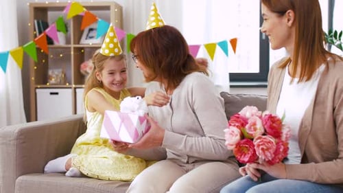 Three Generations Celebrating Birthday with Gift and Flowers