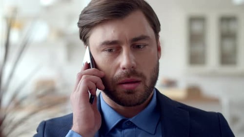 Serious businessman speaking on mobile phone emotionally at home office in slow motion
