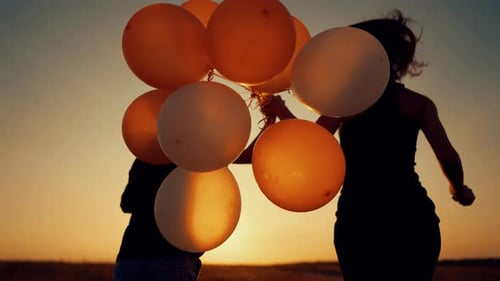 Happy Mother and Little Son Holding Hands and Walking in Field Balloons in Hand Calm Scenery in