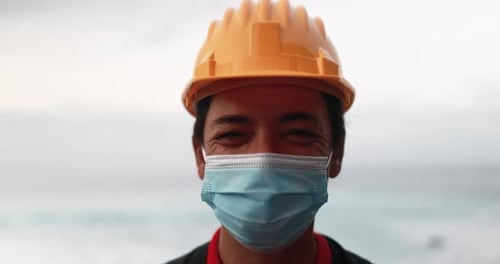 Man wearing hardhat and mask with ocean background