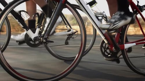 Two young cyclists pedaling road bicycles at sunset achieving fitness goals