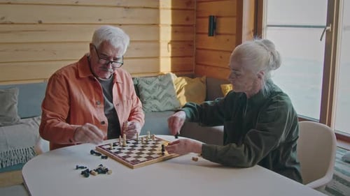 Senior Couple Plays Chess Game in Sunny Room