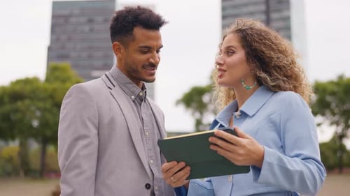 Business Professionals Discussing Work on a Tablet Outdoors