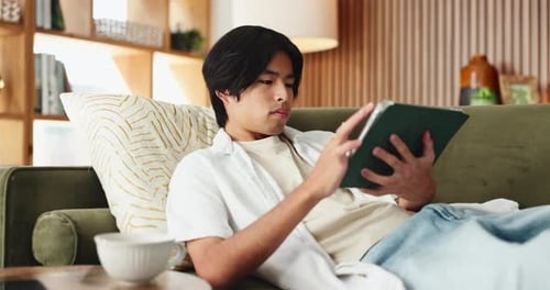 Asian man, student and relax with tablet in house for education results of university application