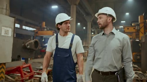 Worker and Engineer Walking through Factory, Discussing Manufacturing Process