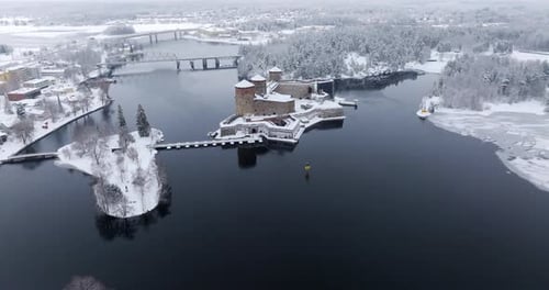 Aerial view tilting toward the snowy Olavinlinna castle, winter day in Finland
