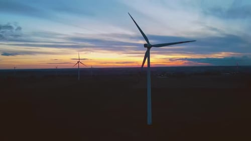 Working Wind Farm with Windmill Turbines Park Aerial View at Amazing Cloudy Colorful Sunset