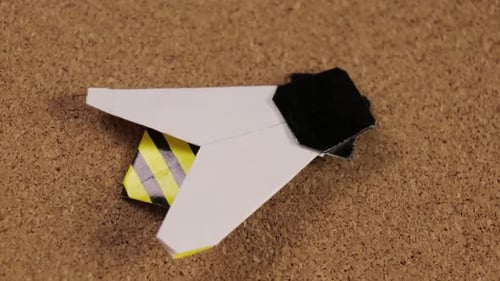 Paper bee made with the origami technique. Cork surface for crafts. Close up.