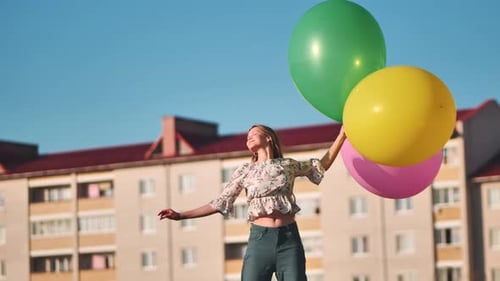 A Girl Happily Poses with Large with Colorful Balloons in the City