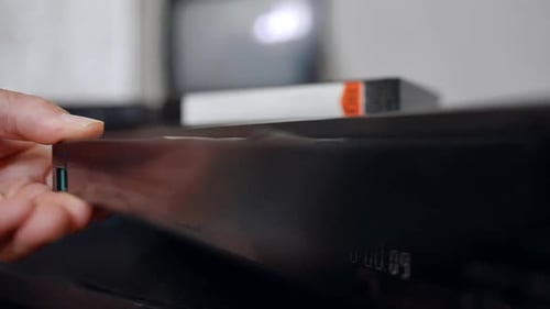 Male hand places the VHS tape into the recorder. Extreme close-up.