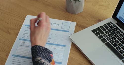 Woman Filling and Signing Tax Form at Desk