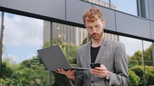 Young Adult Using Phone and Laptop Outdoors