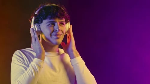 Young Adult Enjoys Music with Headphones in Studio