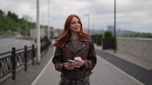 Woman with Coffee Walking in City Using Phone