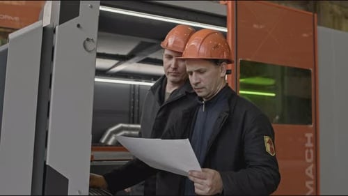 Workers Look at Paper and Industrial Computer Stock Clip Checking Settings of Industrial Computer