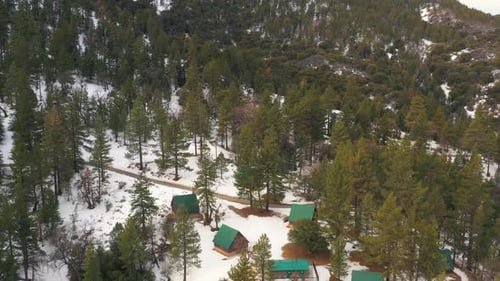 Cabins in the snowy pine forest of the Tehachapi mountains in winter - aerial view