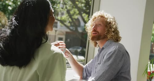 Happy diverse couple drinking coffee and talking in cafe