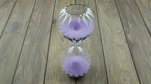 Lilac Hourglass On A Wooden Background.