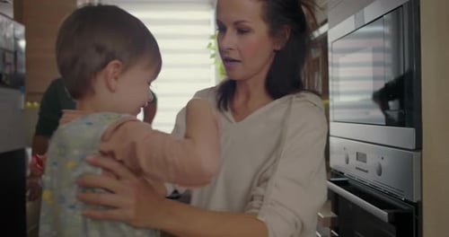 Mother With Child in Kitchen With Man in Background