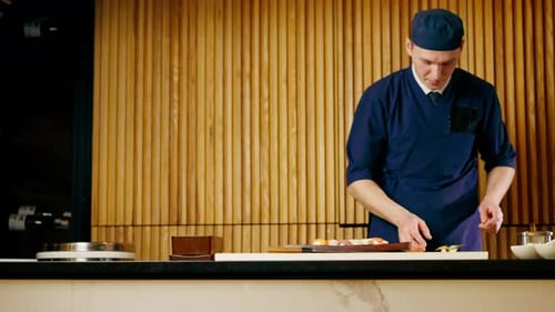 in Japanese Restaurant the Chef Lays Out Pieces of Raw Fish on a Long Red Plate