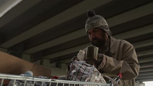 Man outdoors pours liquid into mug