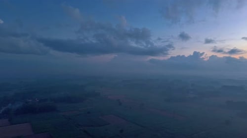 Aerial View of Sunrise Over Misty Rural Landscape