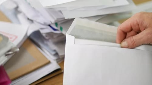 Close up of a man opening debt letters. The letter shows a credit card bill overdue