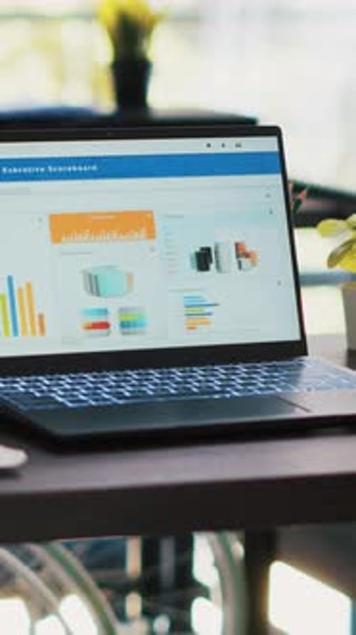 Vertical Video Wheelchair in Inclusive Office and Laptop Showing Marketing Report Data