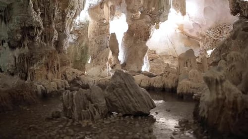 Cave limestone underground with white stalactites and stalagmites riding through an illuminated tunn