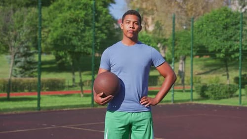 Portrait d'un joueur de basket-ball noir déterminé et sportif tenant le ballon sur le terrain