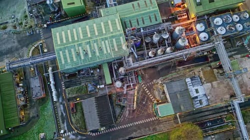 Rotating Overhead drone aerial footage of a large industrial plant showing pipework structures, buil