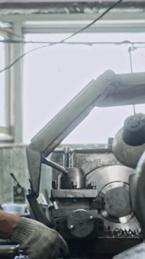 Experienced worker operating metal lathe in industrial workshop