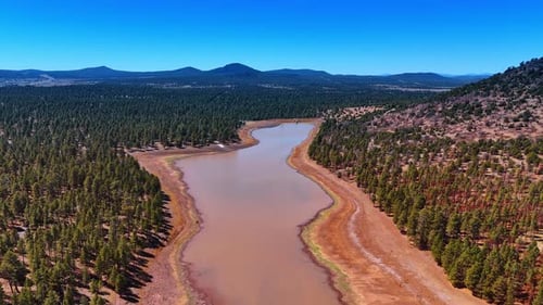 Footage over the shallow river with brown water and banks.