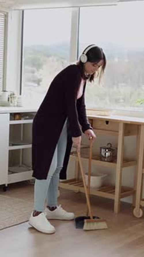 Woman Sweeping Kitchen Floor with Headphones On