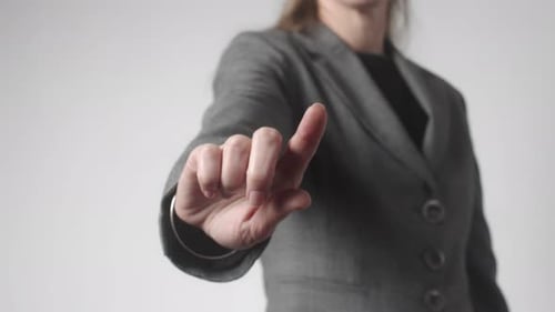 An Adult Woman in a Gray Business Suit Stands and Extends Her Hand Forward with Her Index Finger