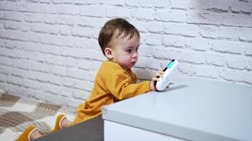 Cute Baby Plays with a Toy Phone Indoors