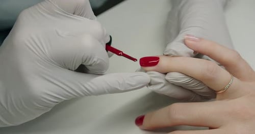 Applying Red Nail Polish in Beauty Salon