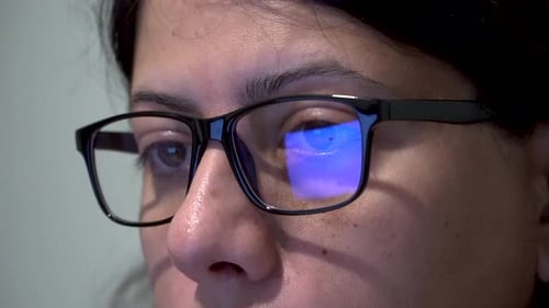 Woman with Glasses Working on Computer, Screen Reflection on Glass, Close up Shot
