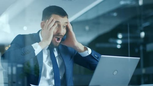 In the Office Businessman Sitting at the Desk Using Laptop Finishes Project and Wins Big. Makes Suc