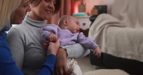 Happy female gay couple having tender moment with their baby son at home