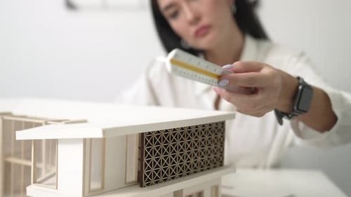 Professional architect using triangular scale measure house model. Immaculate.