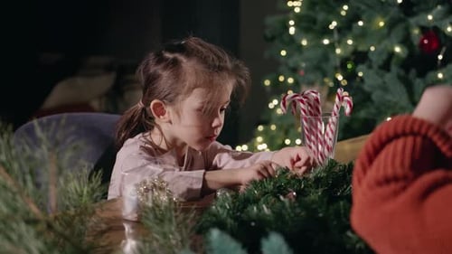 Child Decorating Christmas Wreath with Adult Assistant