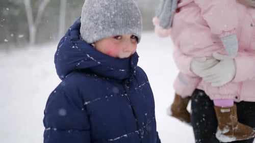 Junge mit Familie geht im Urlaub unter Schneefall durch den Winterwald Vater Mutter Sohn und