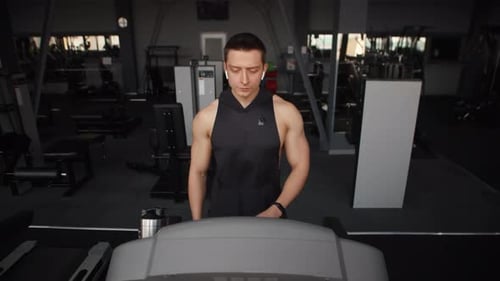 Junger kaukasischer Sportler baut seinen Fitness-Tracker auf und fängt an, auf dem Laufband zu laufen