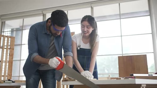 Man and Woman in Workshop Sawing Wood