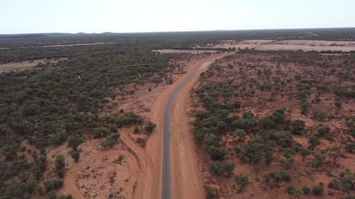 Aerial view of a Country road surrounded by red soil in the Australian Outback