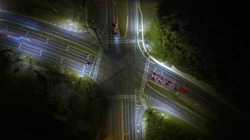 Large intersection de rues à voies multiples avec des feux de circulation et des voitures en mouvement la nuit Timelapse de